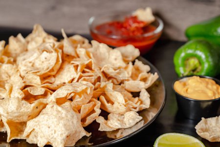 Closeup of a taco salad in a tortilla shell with chips. plate with taco, nachos chips and tomato dip
