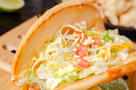Nahaufnahme eines Taco-Salats in einer Tortilla-Schale mit Chips. Teller mit Taco, Nachos-Chips und Tomatendip