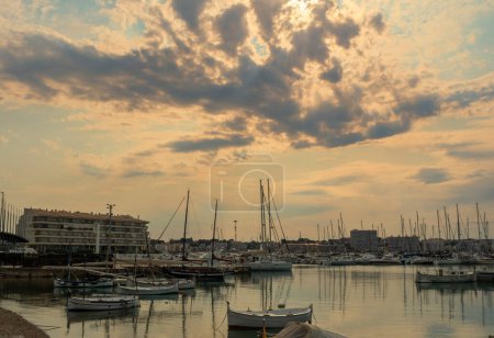 Téléchargez les photos : Bateaux dans le port au coucher du soleil avec ciel nuageux - en image libre de droit