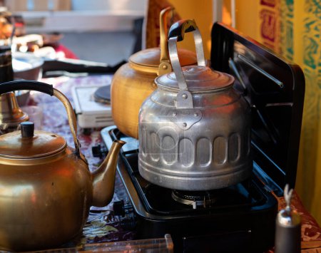 Téléchargez les photos : Préparation du thé dans une tente avec un poêle portable - en image libre de droit
