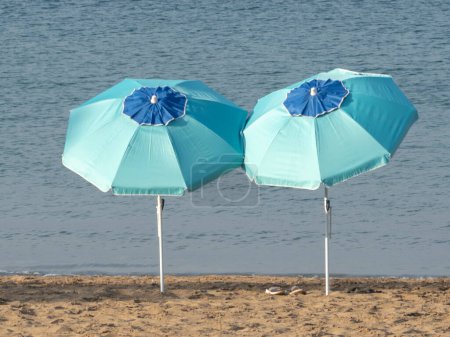 Téléchargez les photos : Deux parasols sur une plage de la mer Méditerranée - en image libre de droit