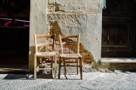 Téléchargez les photos : Pienza, Toscane : deux chaises avec des sièges en paille le long de la rue dans le centre historique - en image libre de droit
