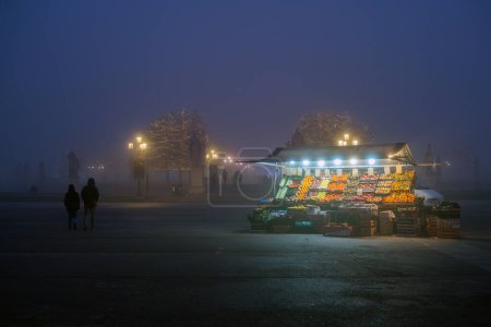 Foto de Padua, Italia - 14 de diciembre de 2023: Quiosco de frutas y verduras en Prato della Valle inmerso en la niebla. - Imagen libre de derechos