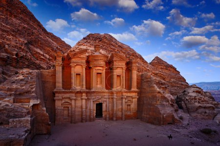 Téléchargez les photos : Travel in Jordan, Arabia in Asia. Stone Monastery in rock, Petra in Jordan. Red rock landcape. Petra historical sight - Ad Deir Monastery with blue sky and white clouds. Evening light in nature. - en image libre de droit