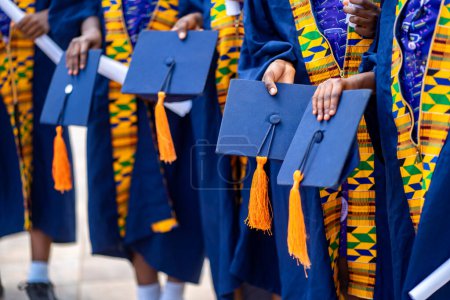 Foto de Enfoque selectivo de los africanos, en sombrero de mano uniforme, gente de color negro en ropa tradicional de pie en la línea exterior- concepto de graduación - Imagen libre de derechos