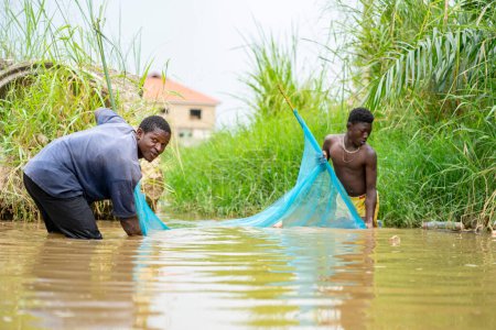Foto de Imagen de chicos africanos en una red fluvial - concepto de recolección de peces - Imagen libre de derechos