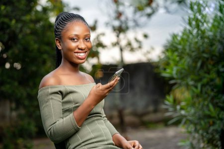 Foto de Beautiful young african american girl talking on mobile phone while using her smartphone. - Imagen libre de derechos