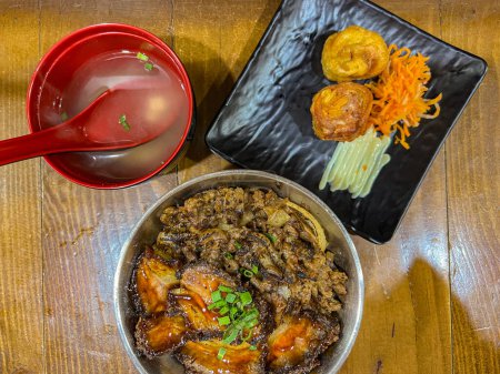 Japanese food called Buta Don or Gyu Don or Beef Rice Bowl or Pork Rice Bowl served with miso soup and fried egg roll. 