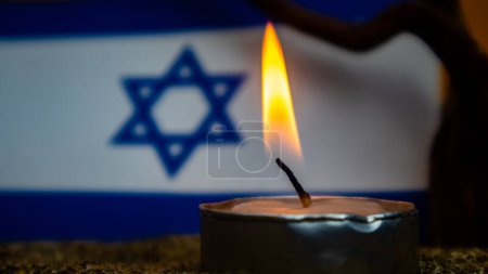 Bandera israelí y velas encendidas frente a ella, Día de la Memoria del Holocausto
