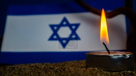 Bandera israelí y velas encendidas frente a ella, Día de la Memoria del Holocausto