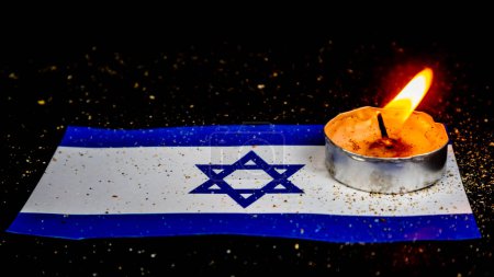 Bandera de Israel y velas encendidas encima, Día de la Memoria del Holocausto