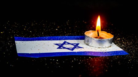 Bandera de Israel y velas encendidas encima, Día de la Memoria del Holocausto