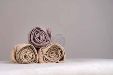 Téléchargez les photos : Gros plan d'une composition avec trois serviettes torsadées sur une table de massage dans un spa, espace de copie - en image libre de droit