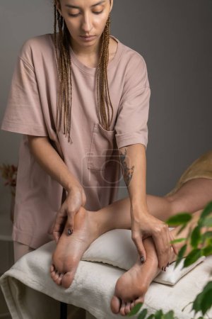 Téléchargez les photos : Masseur donne un massage des pieds à une jeune femme dans un salon de spa dans une atmosphère agréable. Concept de santé, soins du corps. Photo verticale - en image libre de droit