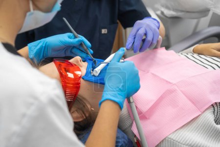 Téléchargez les photos : Un dentiste en gros plan procède à un assainissement buccal avec de l'eau avant le traitement dentaire d'un patient dans une clinique dentaire. Le dentiste effectue le nettoyage dentaire, le traitement et le remplissage des canaux. - en image libre de droit