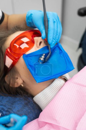 Der Zahnarzt untersucht die Zähne eines Patienten mit einer Kassa. Zahnarzthände mit medizinischen Instrumenten. Konzept der gesunden Zähne. Vertikales Foto
