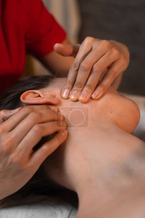 Téléchargez les photos : Gros plan des mains d'un masseur faisant un massage facial à une jeune femme brune dans un salon de spa. Concept de santé et de beauté. Photo verticale - en image libre de droit