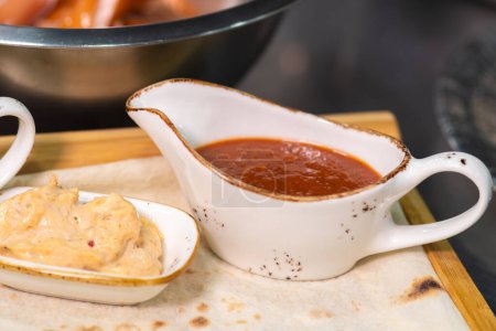 Photo for Close-up of various sauces in speckled white saucepans on a wooden tray with pita bread - Royalty Free Image