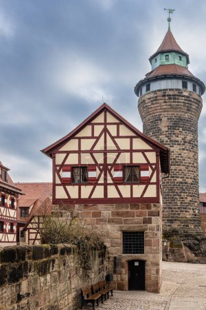 Foto de Edificio de entramado de madera en el patio del Castillo Imperial y la Torre Sinwell en el fondo. Nuremberg, Baviera, Alemania. - Imagen libre de derechos