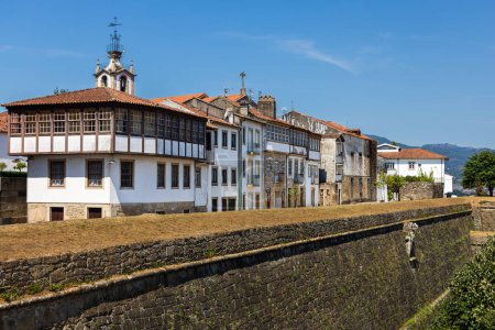 Die alten Stadtmauern der Festung Valenca überragen eine charmante Straße, gesäumt von klassisch weißen portugiesischen Häusern mit leuchtend roten Dächern. Valenca, Portugal.