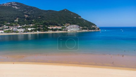 Aerial view of Playa de San Martin sandy beach, the azure waters of Santoa Bay, mountains, and the city of Santona in the distance. Laredo, Cantabria, Spain.