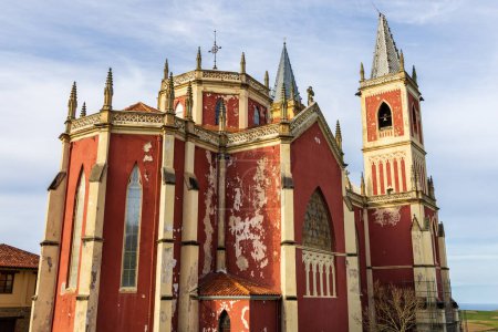 Die leuchtend rote Pfarrkirche San Pedro Ad Venceya mit zwei Türmen im französischen neogotischen und indianischen Stil mit neoklassischen, barocken und modernistischen Elementen. Cobreces, Kantabrien, Spanien.