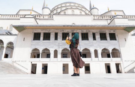 Téléchargez les photos : Moyen-Orient jeune femme prenant des photos avec le téléphone. mosquée photo veste femme musulmane - en image libre de droit