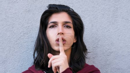 Foto de Persona no binaria mirando a la cámara sosteniendo el dedo en los labios símbolo, pidiendo silencio, silencio. Persona gay - Imagen libre de derechos