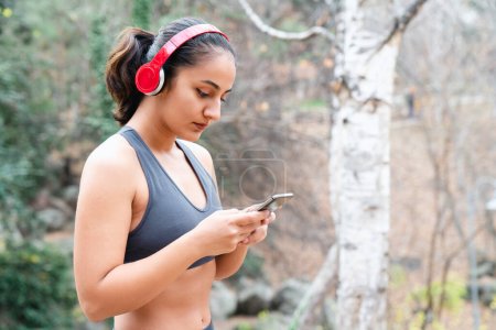 Foto de Mujer usando un smartphone y auriculares después del entrenamiento - Imagen libre de derechos