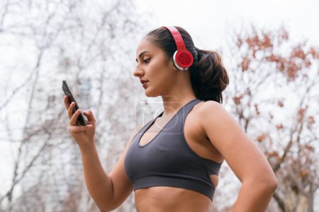 Photo for Woman using a smartphone and headphones after workout - Royalty Free Image