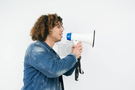 Photo for Young man holding a megaphone while posing against a white background - Royalty Free Image