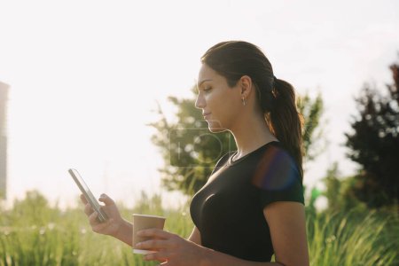 Foto de Mujer joven usando el teléfono inteligente y haciendo ejercicio al aire libre en la ciudad - Imagen libre de derechos