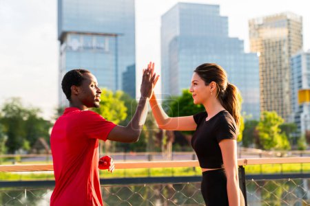 Photo for Full length of cheerful young couple giving high-five during sunset. They are in sportswear. - Royalty Free Image