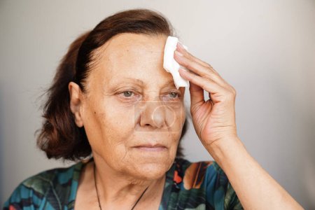 Foto de Mujer mayor sudando sufriendo un golpe de calor en casa - Imagen libre de derechos