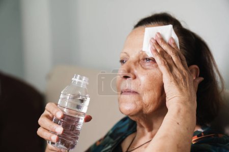 mujer mayor sudando sufriendo un golpe de calor en casa