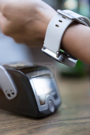 Téléchargez les photos : Femme payant sans contact avec smartwatch dans le restaurant - en image libre de droit