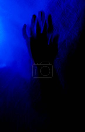Téléchargez les photos : Bras de femme pressant contre le rideau. silhouette femme derrière la lumière bleue pose mystérieusement et artistiquement - en image libre de droit