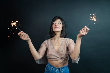 Photo for Happy beautiful woman holding festive sparklers among Christmas night - Royalty Free Image