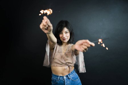 Photo for Happy beautiful woman holding festive sparklers among Christmas night - Royalty Free Image