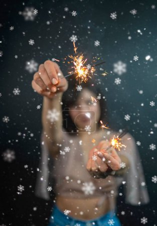 Foto de Feliz hermosa mujer sosteniendo chispas festivas entre la noche de Navidad - Imagen libre de derechos