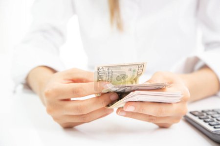 Téléchargez les photos : De l'argent entre les mains. Femme méconnaissable comptant les billets en dollars américains - en image libre de droit