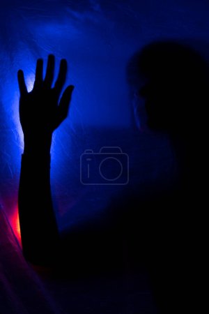 Téléchargez les photos : Silhouette femme derrière la lumière bleue pose mystérieusement et artistiquement - en image libre de droit