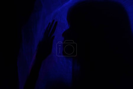 Foto de Mujer silueta detrás de la luz azul plantea misteriosa y artísticamente - Imagen libre de derechos