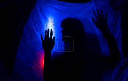 Téléchargez les photos : Silhouette femme derrière la lumière bleue pose mystérieusement et artistiquement - en image libre de droit