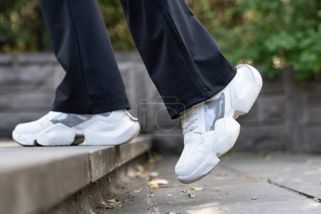 Téléchargez les photos : Section basse de la femme en baskets blanches courant sur les escaliers dans le parc - en image libre de droit