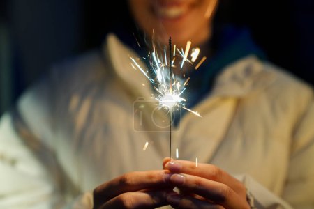 Photo for Woman holding burning sparkler during Christmas - Royalty Free Image
