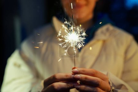 Photo for Woman holding burning sparkler during Christmas - Royalty Free Image