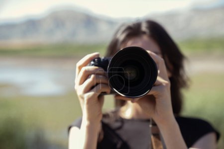 Téléchargez les photos : Jeune femme utilisant un appareil photo reflex numérique. Jeune femme photographe avec objectif photo - en image libre de droit