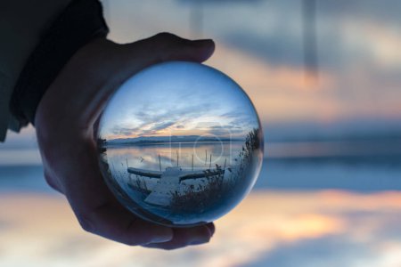 Photo for View of nature through a glass ball, summer sunset time. hand holding crystal glass ball against nature background with reflections - Royalty Free Image
