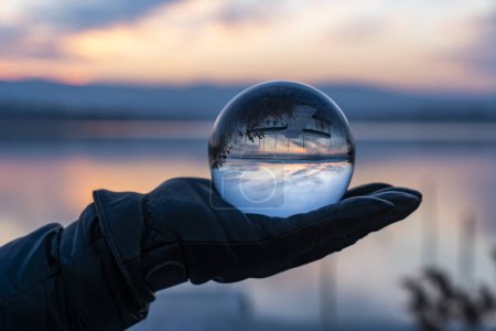 Photo for View of nature through a glass ball, summer sunset time. hand holding crystal glass ball against nature background with reflections - Royalty Free Image